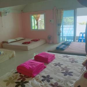 a bedroom with two beds with pink sheets on the floor at Savina Homestay in Ban Batubute