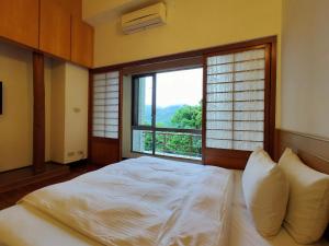 um quarto com uma cama e uma janela grande em 復興青年活動中心 復興比雅山會館 em Fuxing