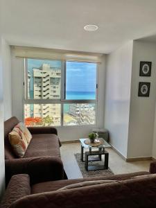 Una sala de estar con un sofá y una ventana grande. en Suite vista al Mar Salinas, en Salinas