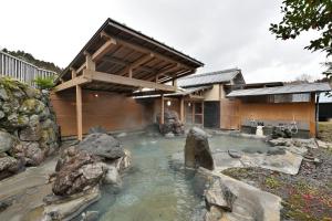a house with a pond in front of it at Shikinosato Hanamura in Minamioguni