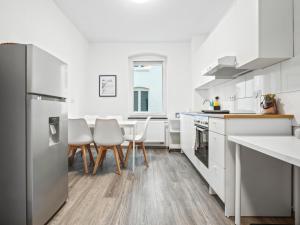 una cocina con electrodomésticos blancos, mesa y sillas en Wohnung in zentraler Lage - Kostenlose Parkplätze, en Kassel