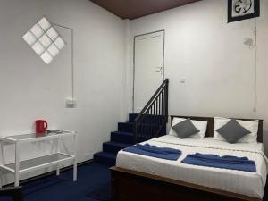 a bedroom with a bed with blue sheets and a staircase at YaYa Lodge Haputale in Haputale