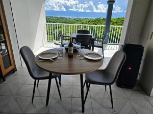 a table and chairs on a balcony with a view of the ocean at Maison (Vu sur le Lagon) in Le Gosier