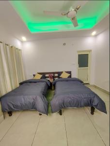 two beds in a bedroom with a green ceiling at Blissful stays midst nature in Rishīkesh +1 photo