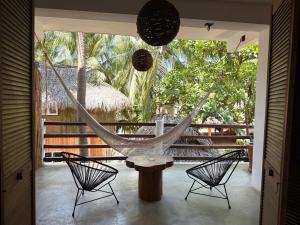a hammock on a porch with two chairs at Bikini Beach House in Puerto Escondido