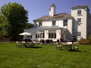 a large white house with tables and chairs in the yard at Fishmore Hall Hotel and Boutique Spa in Ludlow