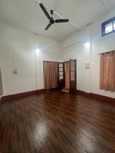 Habitación vacía con ventilador de techo y suelo de madera. en Sri Sam Homestay, en Sibsāgar