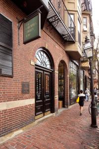 a woman walking down a brick sidewalk in front of a building at 94 Charles Street by Thatch in Boston