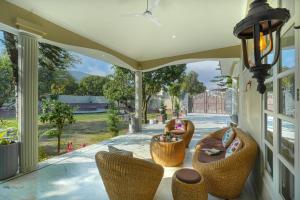 a porch with wicker chairs and a table at SaffronStays Mont Tierra - 4BR modern villa with lawn, bonfire, indoor games & themed rooms, Dehradun in Dehradun
