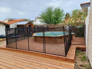 a hot tub on a deck with a fence at Villa avec piscine L'Abris Côtier in Mimizan