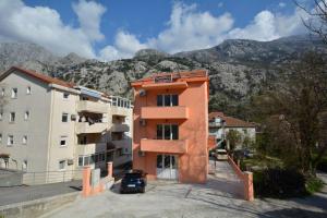 an orange building with mountains in the background at Marinero Apartments in Kotor