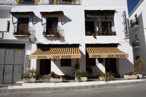 un edificio blanco con ventanas y balcones con plantas en Hotel Rural San Roque en Pitres