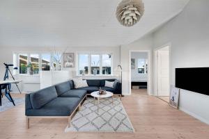 a living room with a blue couch and a table at Sea View And Charging Station For Electric Car in Hjørring