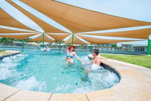 a man and woman playing in a swimming pool at Club Tropical Resort Darwin in Darwin