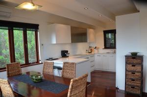 een keuken met een tafel en stoelen en een keuken met witte werkbladen bij Yolla Beach House in Adventure Bay