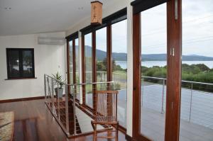 a house with a balcony with a view of the water at Yolla Beach House in Adventure Bay