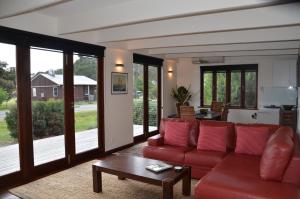 Yolla Beach House في Adventure Bay: غرفة معيشة مع أريكة حمراء وطاولة