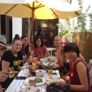 Eine Gruppe von Menschen, die an einem Tisch sitzen und Essen essen. in der Unterkunft Blue Lake Homestay in Hoi An