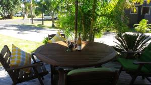 una mesa de madera con una botella de cerveza y sillas en Cathedral Cove Apartment, en Hahei