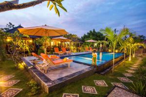 einen Pool mit orangefarbenen Stühlen und einem Sonnenschirm in der Unterkunft Dinatah Lembongan Villas in Nusa Lembongan