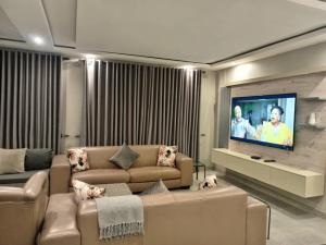 uma sala de estar com um sofá e uma TV de tela plana em Tourice Lodge em Victoria Falls mais 10 fotografias