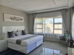 um quarto com uma cama grande e uma janela em Tourice Lodge em Victoria Falls