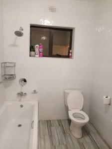 uma casa de banho com um WC, uma banheira e uma janela. em Tourice Lodge em Victoria Falls