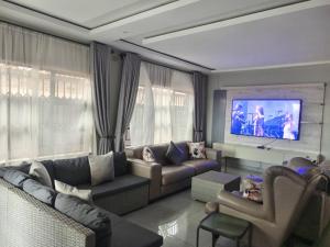 uma sala de estar com um sofá e uma TV de tela plana em Tourice Lodge em Victoria Falls