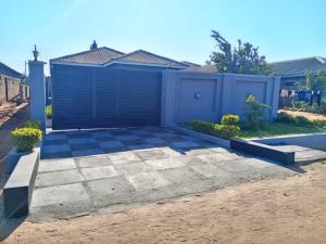 uma casa com um portão azul e uma entrada em Tourice Lodge em Victoria Falls