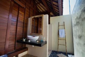 ein Badezimmer mit einem Waschbecken und einer Holzwand in der Unterkunft Dinatah Lembongan Villas in Nusa Lembongan