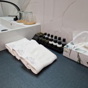 een badkamer met handdoeken, een wastafel en een doos wijn bij Villa Maris in Koper