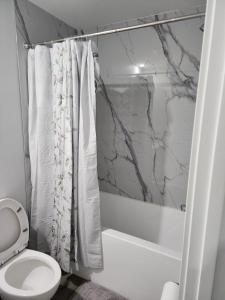 ein Badezimmer mit weißer Toilette und Dusche in der Unterkunft lovely 2bed & 1 Bath Basement Suite for 4 guests in 