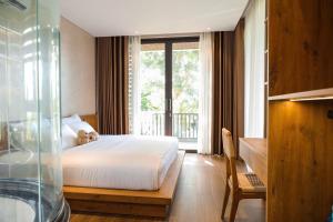 ein Schlafzimmer mit Bett, Schreibtisch und Fenster in der Unterkunft Villa Brisa Tropical BMT in Buôn Kao