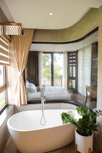 ein großes Bad mit einer Badewanne und einem Bett in der Unterkunft Villa Brisa Tropical BMT in Buôn Kao