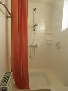 eine Dusche mit orangefarbenem Duschvorhang im Bad in der Unterkunft Ferienbungalow in Seeboden