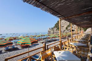 a beach with tables and chairs and umbrellas at Hotel Pupetto in Positano