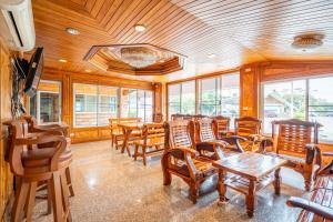 a restaurant with wooden chairs and tables and windows at Chatsuree Mansion in Ubon Ratchathani