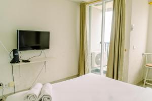 a hotel room with a bed and a tv at Comfort and Homey Studio at Parkland Avenue Apartment By Travelio in Tangerang