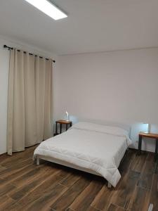 a white bedroom with a bed and wooden floors at Umberto primo rooms in Castelbuono