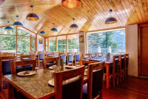 una sala da pranzo con tavoli, sedie e finestre di Hotel Greenfields a Manāli