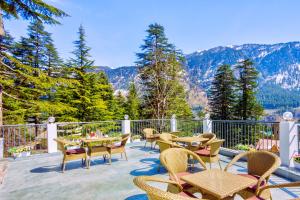 un patio con tavoli e sedie con montagne sullo sfondo di Hotel Greenfields a Manāli