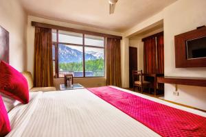 una camera da letto con un letto grande con una grande finestra di Hotel Greenfields a Manāli