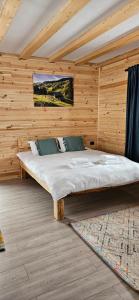 ein Schlafzimmer mit einem Bett in einer Holzwand in der Unterkunft Casuta CORE in Sadová