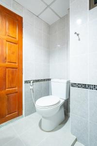 a bathroom with a toilet and a wooden door at Chatsuree Mansion in Ubon Ratchathani