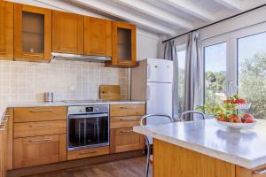 a kitchen with wooden cabinets and a large window at Aretousa - Deluxe Pool Apartment in Skopelos Town