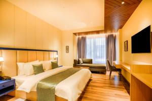 哈尔德瓦尼Hotel Treeline的配有一张大床和一台电视的酒店房间