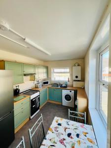 フェリックストウにある4-Bedroom House 5 mins to Beach & Parkingのキッチン(緑のキャビネット、ダイニングルーム付きのテーブル付)