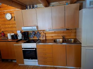 a kitchen with wooden cabinets and a sink and a stove at Rantarinne 543 B in Kuusamo