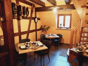 a restaurant with two tables and chairs and a clock at Ferme du Mouton Noir in Lautenbachzell