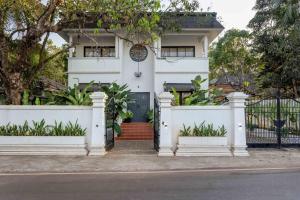 a white house with a black door and a fence at Wadi House - Lux 3BR Villa in Siolim, 4km to beach in Siolim